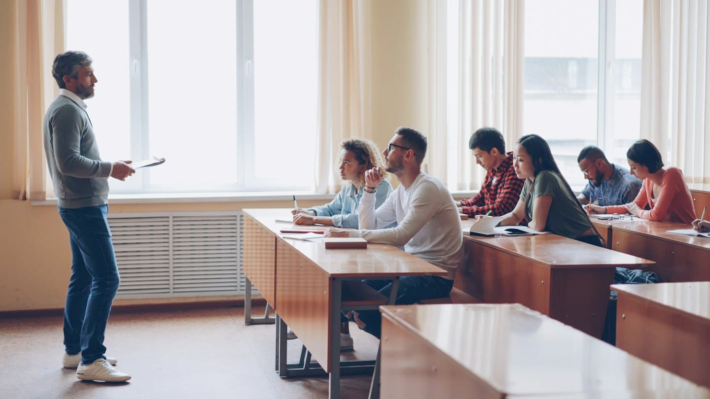 Instructor speaks to students in a bright classroom.